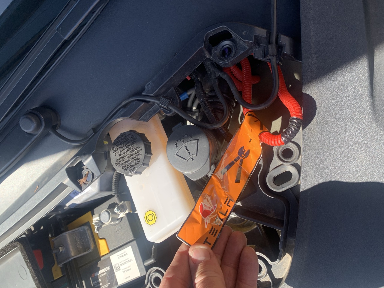 Gloved hand pulling a high-voltage disconnect on an electric vehicle